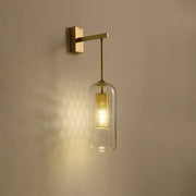 Modern gold mesh and clear glass sconce with a brass frame and illuminated bell-shaped glass sconce shade for bedroom use
