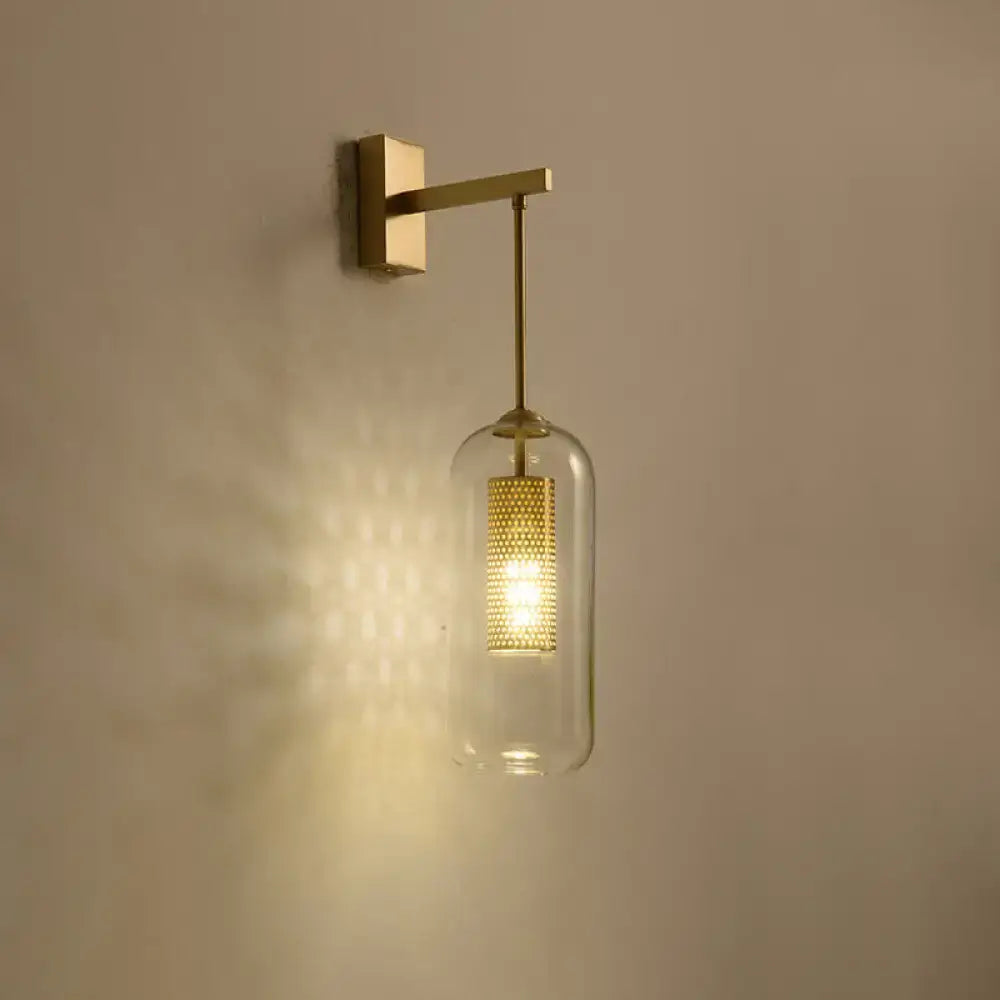 Modern gold mesh and clear glass sconce with a brass frame and illuminated bell-shaped glass sconce shade for bedroom use