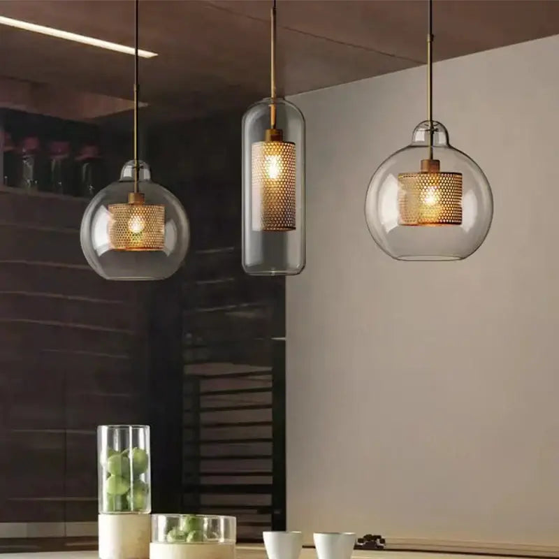 Three modern pendant lights with gold mesh glass ball interiors hang from brass chains for kitchen dining room decorbites