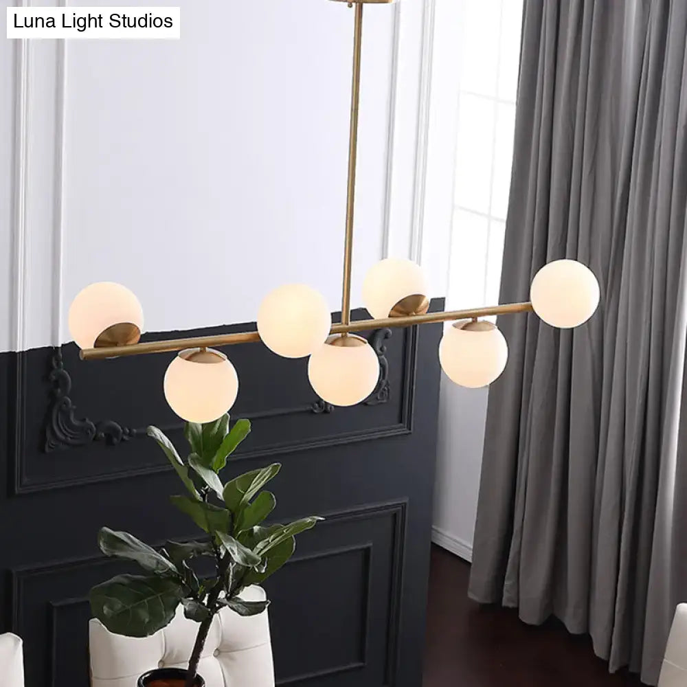Modern gold metal chandelier with five frosted white glass globe shades for dining room island lighting