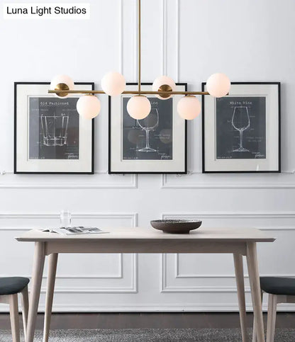 Modern gold metal chandelier with brass finish and six white glass frosted globe lights for dining room island lighting