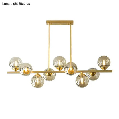 Modern gold metal chandelier with multiple spherical amber glass bulbs for dining room island lighting
