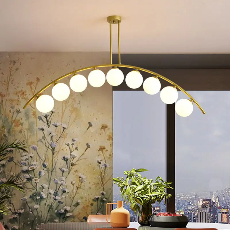 Modern gold metal arched ceiling light with nine spherical glass bulbs for dining room illumination