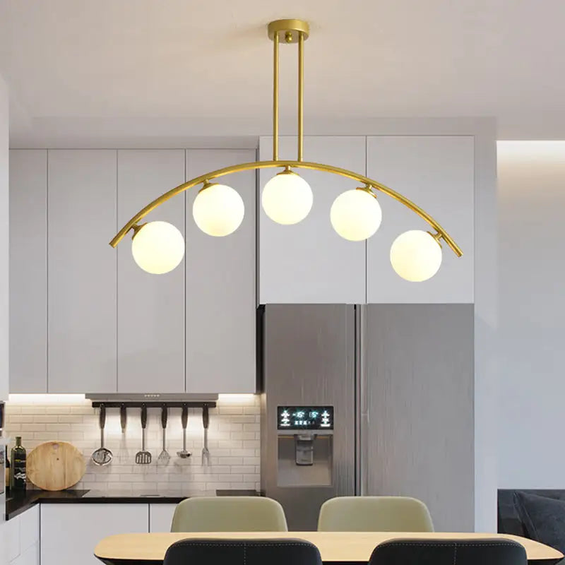 Modern gold metal arched ceiling light with five frosted glass globe bulbs for dining room use