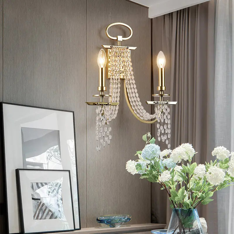Modern gold metal candle wall sconce with two crystal candle bulbs and cascading glass beads for living room light