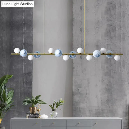 Modern gold metal glass globe chandelier with brass frame and chain cord length featuring blue and white spheres above dining table