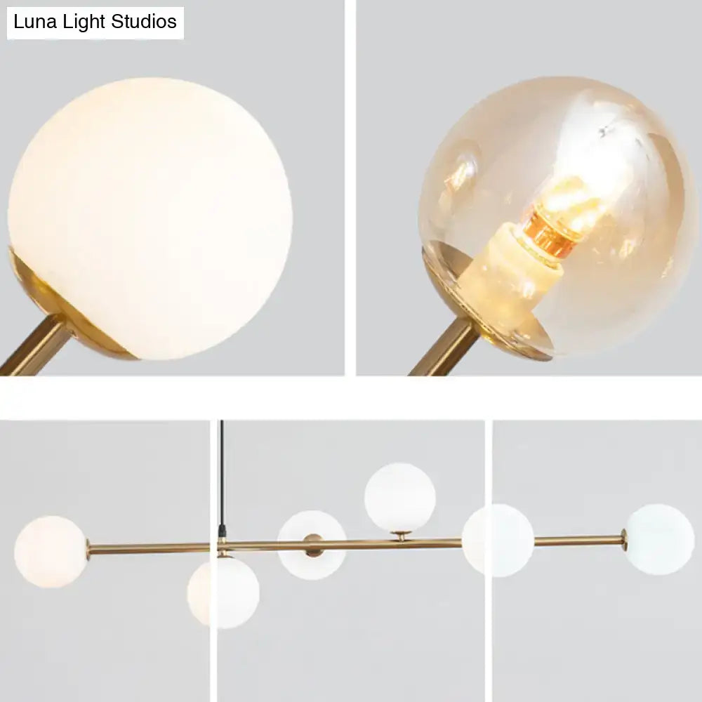 Modern gold metal island pendant with brass finish and frosted glass globe shades for dining room lighting