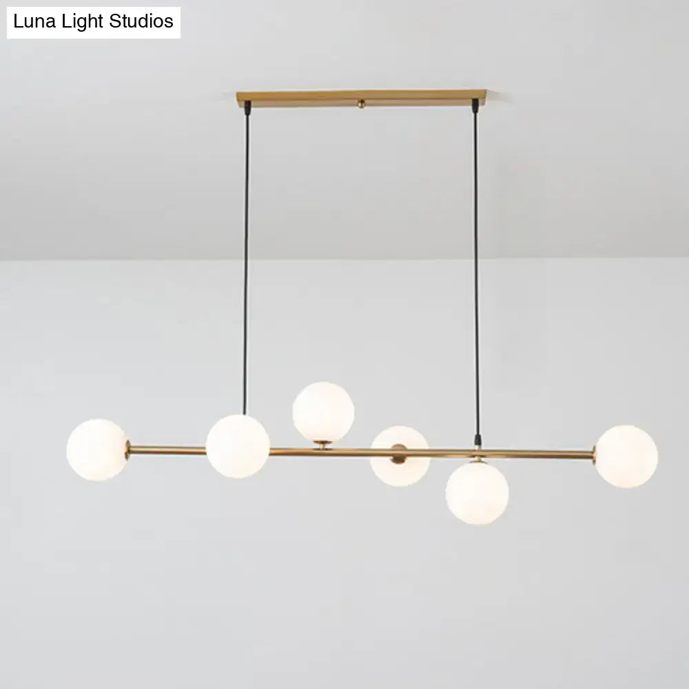 Modern gold metal island pendant with five frosted glass globe bulbs on black cords suspended from wooden mount