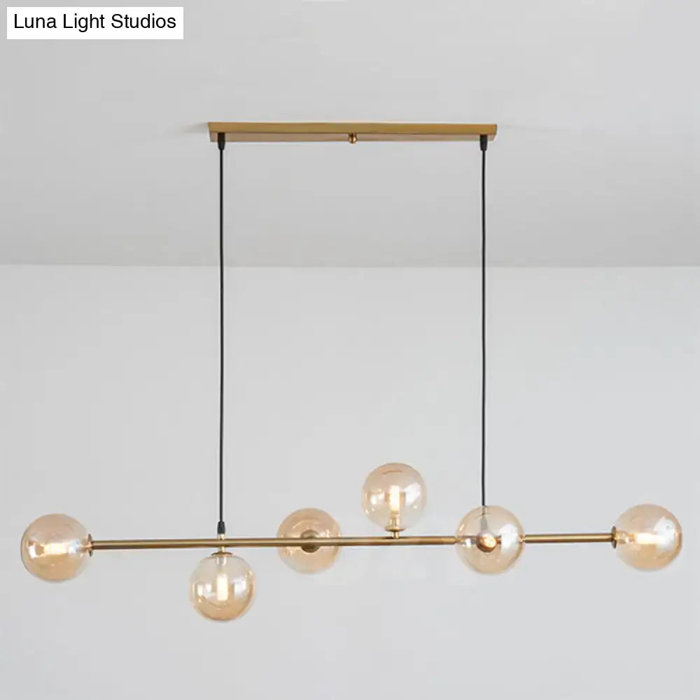 Modern gold metal island pendant featuring five amber glass globes with brass and blue glass accents for dining rooms