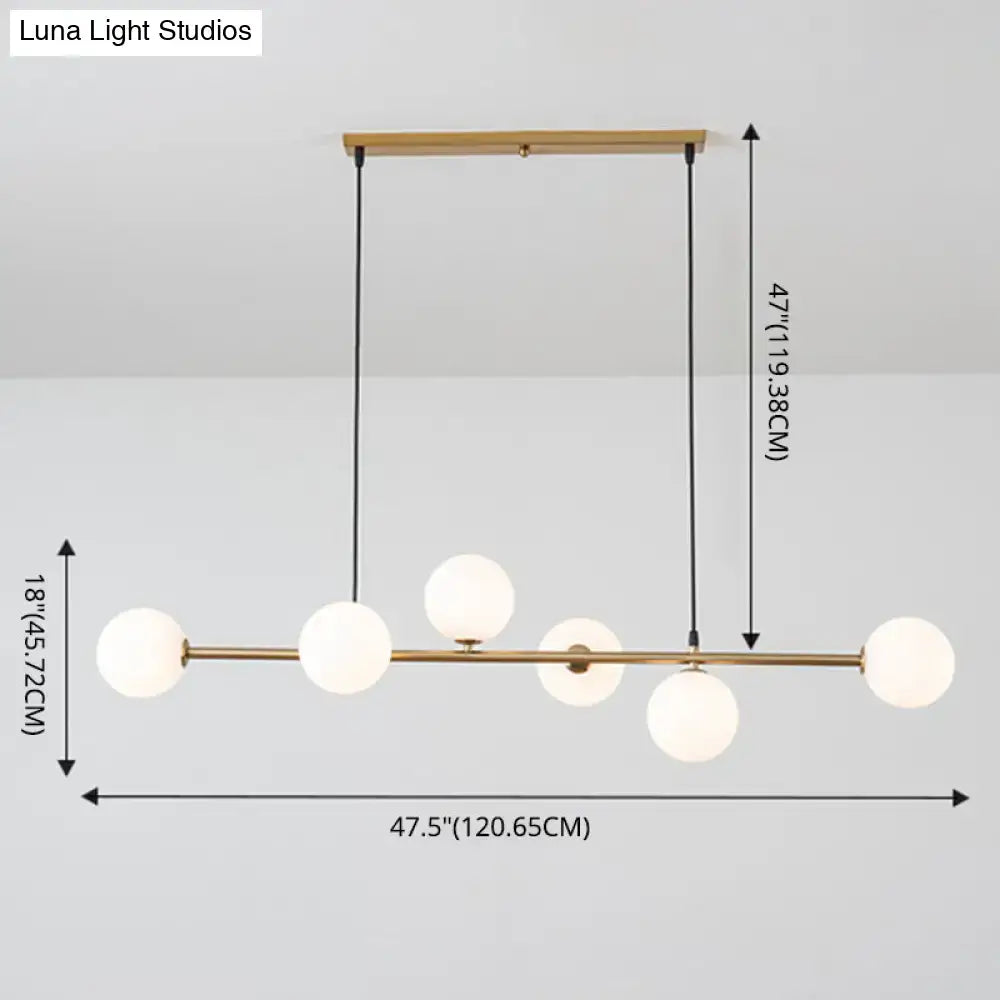Modern gold metal pendant light with five frosted glass globes suspended from wooden ceiling mount for dining room