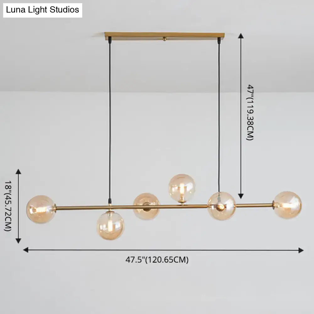 Modern gold metal island pendant with five amber glass bulbs and black cords suspended from wooden ceiling mount