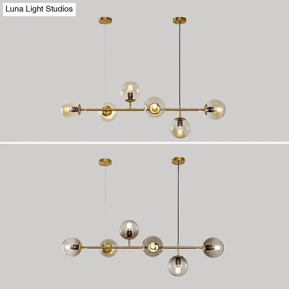 Modern gold metal island pendant with brass finish and blue glass spheres featuring clear and smoked globe shades