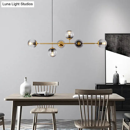 Modern gold metal island pendant with blue glass spheres and brass globes hanging above wooden dining table