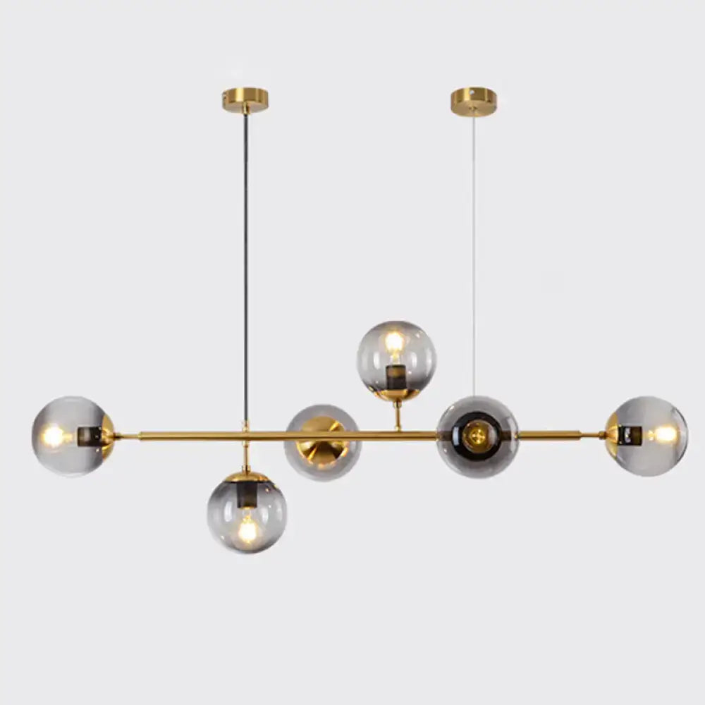 Modern gold metal island pendant with six smoked glass globes and central bar for dining room lighting