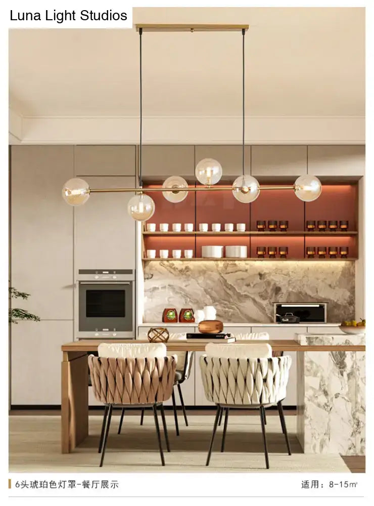 Modern gold metal island pendant with six blue glass spheres suspended from a slender brass bar for dining room