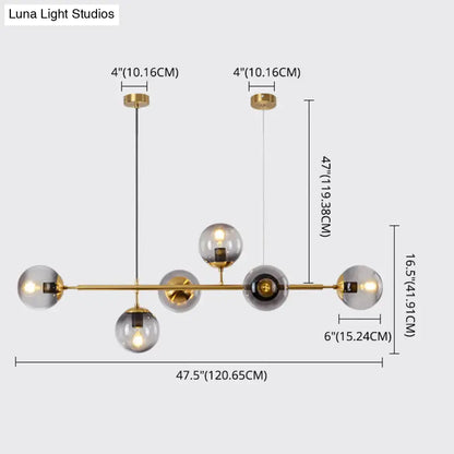 Modern gold metal island pendant featuring a gold-toned chandelier with six smoked glass globe bulbs for dining room use