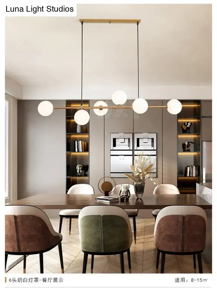 Modern gold metal island pendant with six white glass spherical bulbs suspended from a slender gold metal bar
