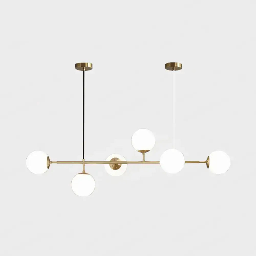 Modern gold metal island pendant light with five frosted glass globes on a horizontal bar for dining room use