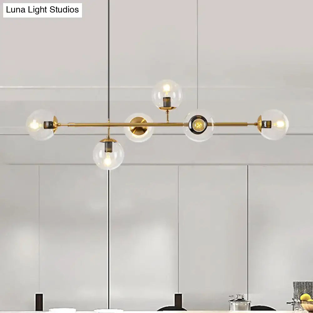 Modern gold metal island pendant with clear glass globe shades and sleek horizontal bar for dining room lighting