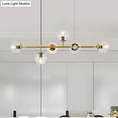 Modern gold metal island pendant with clear glass globe shades and sleek horizontal bar for dining room lighting