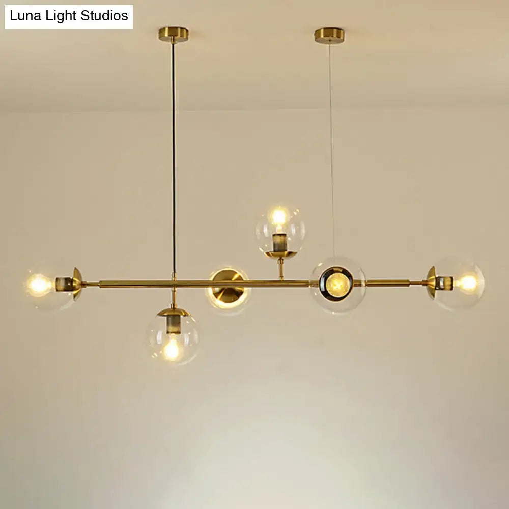 Modern gold metal island pendant with clear glass globe shades and exposed bulbs for dining room lighting