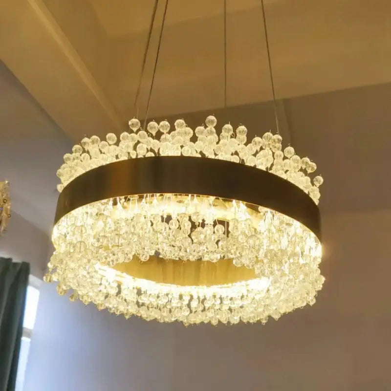 Modern gold metal led chandelier featuring a sleek black metal frame and cascading crystal droplets for dining room decorbites gold metal