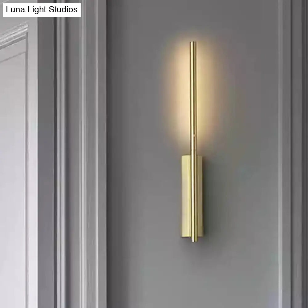 Modern gold metal linear wall light with sleek vertical bars and warm focused light beam for bedroom use