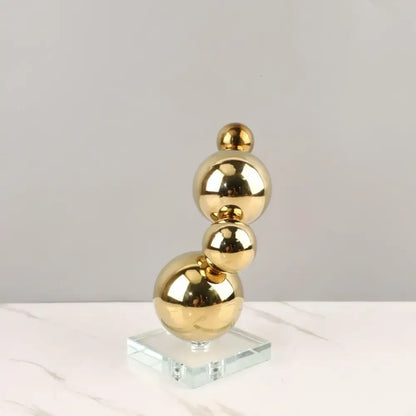 Modern gold metal spheres art pieces stacked vertically on clear glass base living room decorbites gold metal spheres