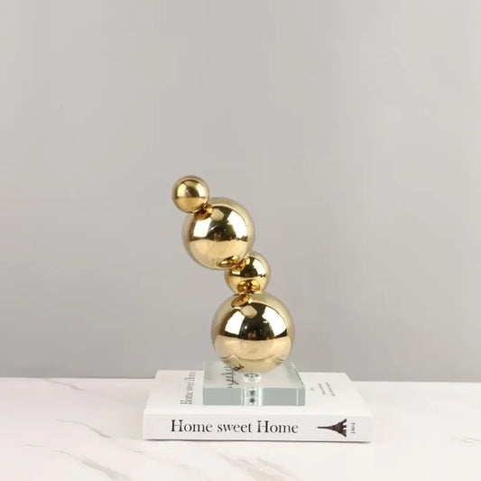 Modern gold metal spheres stacked art piece featuring reflective golden metal spheres on a clear acrylic base decorbites gold metal