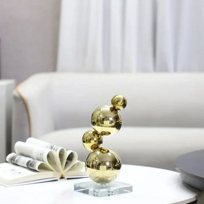 Modern gold metal spheres stacked art pieces on a clear crystal base for elegant living room decorbites gold metal decor