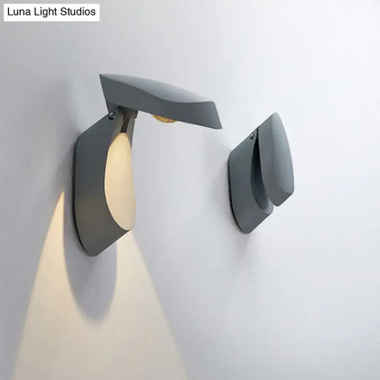 Modern gold metal wall light bedside fixture with sleek matte gray angular design and warm light emission