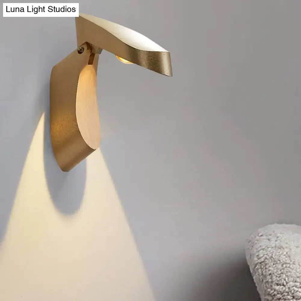 Modern gold metal wall light bedside fixture with sleek sculptural design casting warm light for bedroom