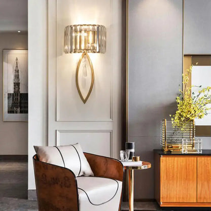 Modern wall light with a gold-toned metallic drum shade and faceted crystal frame for living room decor