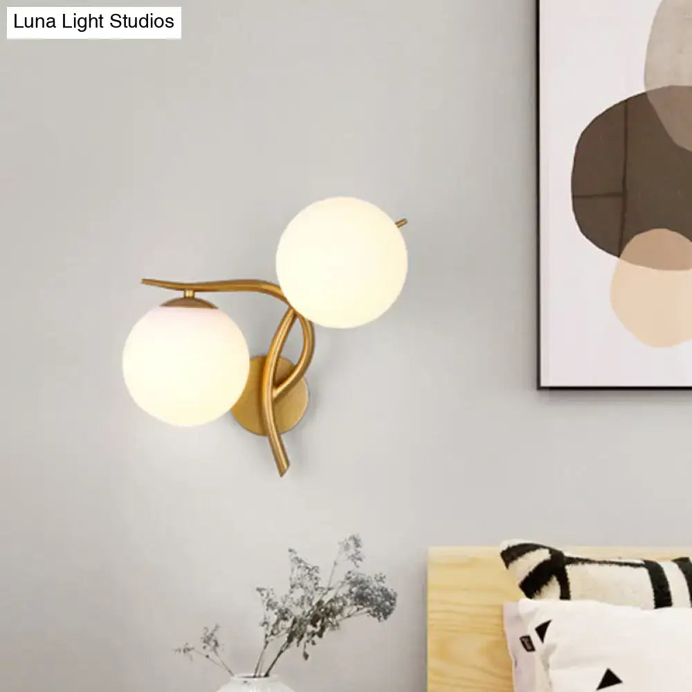 Modern gold sconce light with two frosted milk glass globes and standard bulb base for bedroom wall fixture