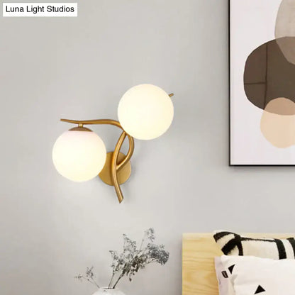 Modern gold sconce light with two frosted milk glass globes and standard bulb base for bedroom wall fixture