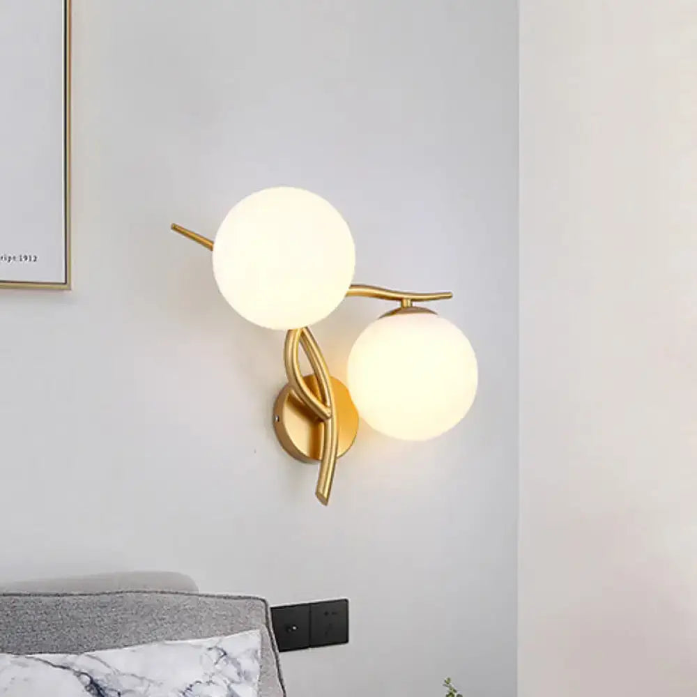 Modern gold sconce light with two milk glass frosted globes and bulb base for bedroom wall fixture