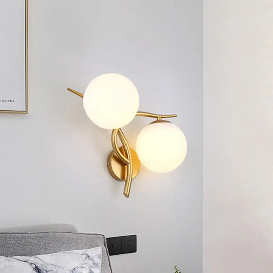Modern gold sconce light with two milk glass frosted globes and bulb base for bedroom wall fixture