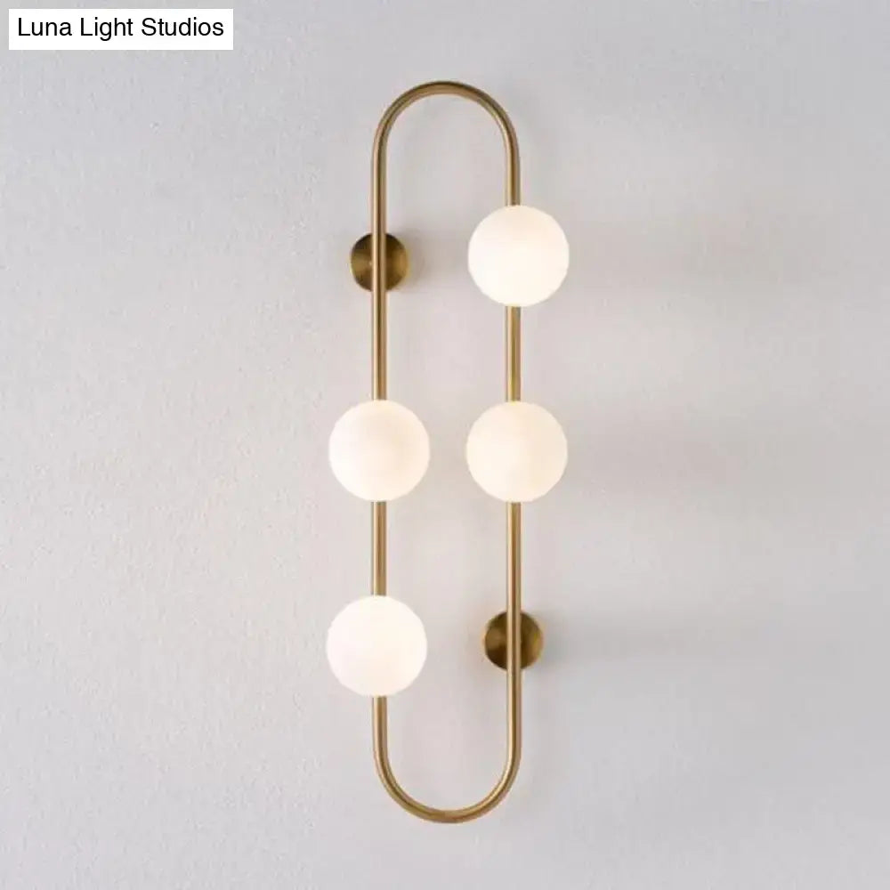 Brass-finished wall light with four frosted milky glass shade globes in a modern vertical curved bedroom sconce design