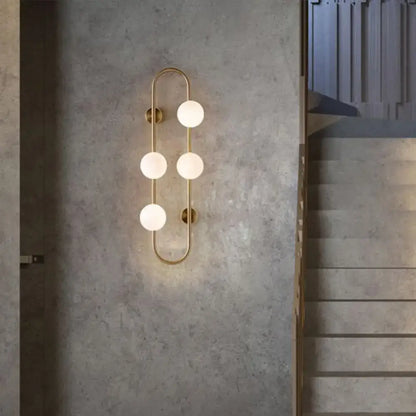 Modern gold wall light with five frosted milky glass shade globes in a vertical curved design for bedroom use