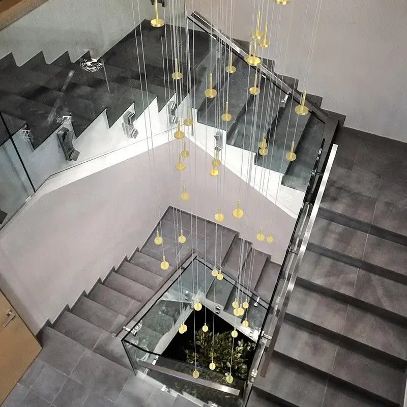 A modern gold minimalist ceiling chandelier with numerous spherical lights suspended by thin cables for living rooms