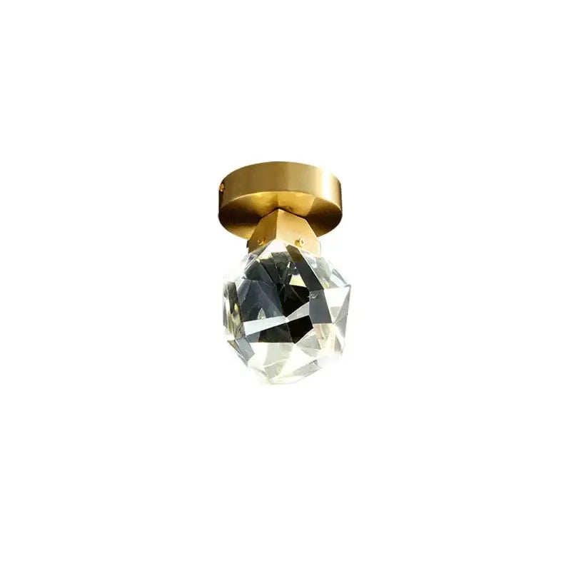 Modern gold minimalist led wall lamp featuring a clear faceted crystal globe suspended from a polished brass plate