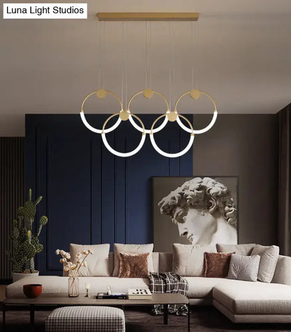 Modern gold minimalistic ring pendant light with illuminated circular rings suspended from wooden ceiling fixture