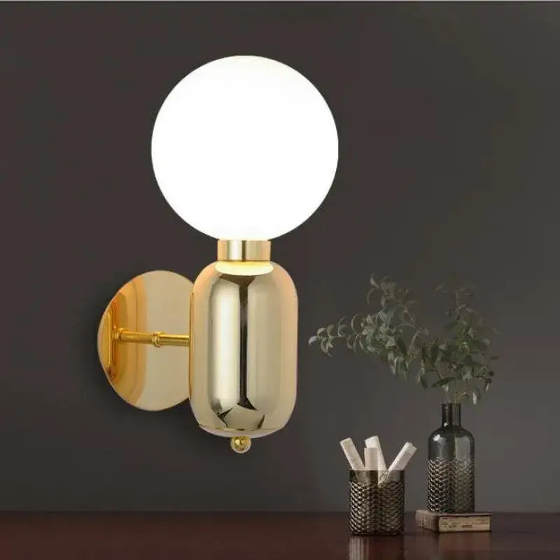 Modern gold mirror ball wall lamp featuring a gold-finished wall sconce with a spherical frosted glass globe