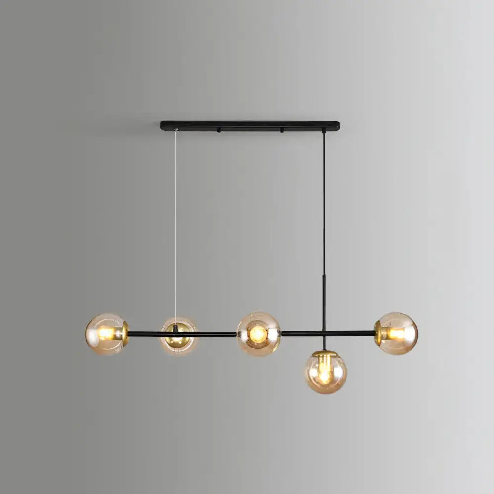 Modern black metal modo island chandelier with five amber glass globe bulbs ideal for restaurants and dining spaces