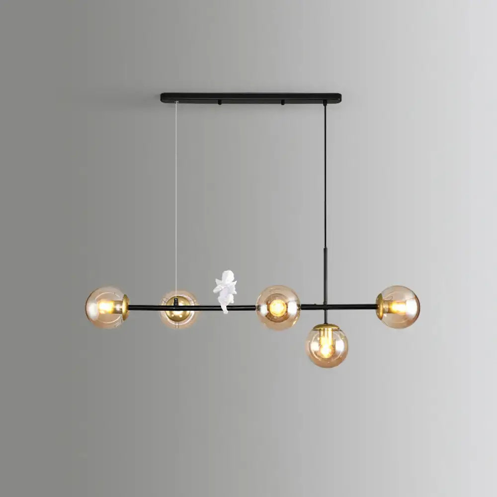 Modern black metal modo island chandelier with five amber glass globes and a small milk white angel figurine for restaurants