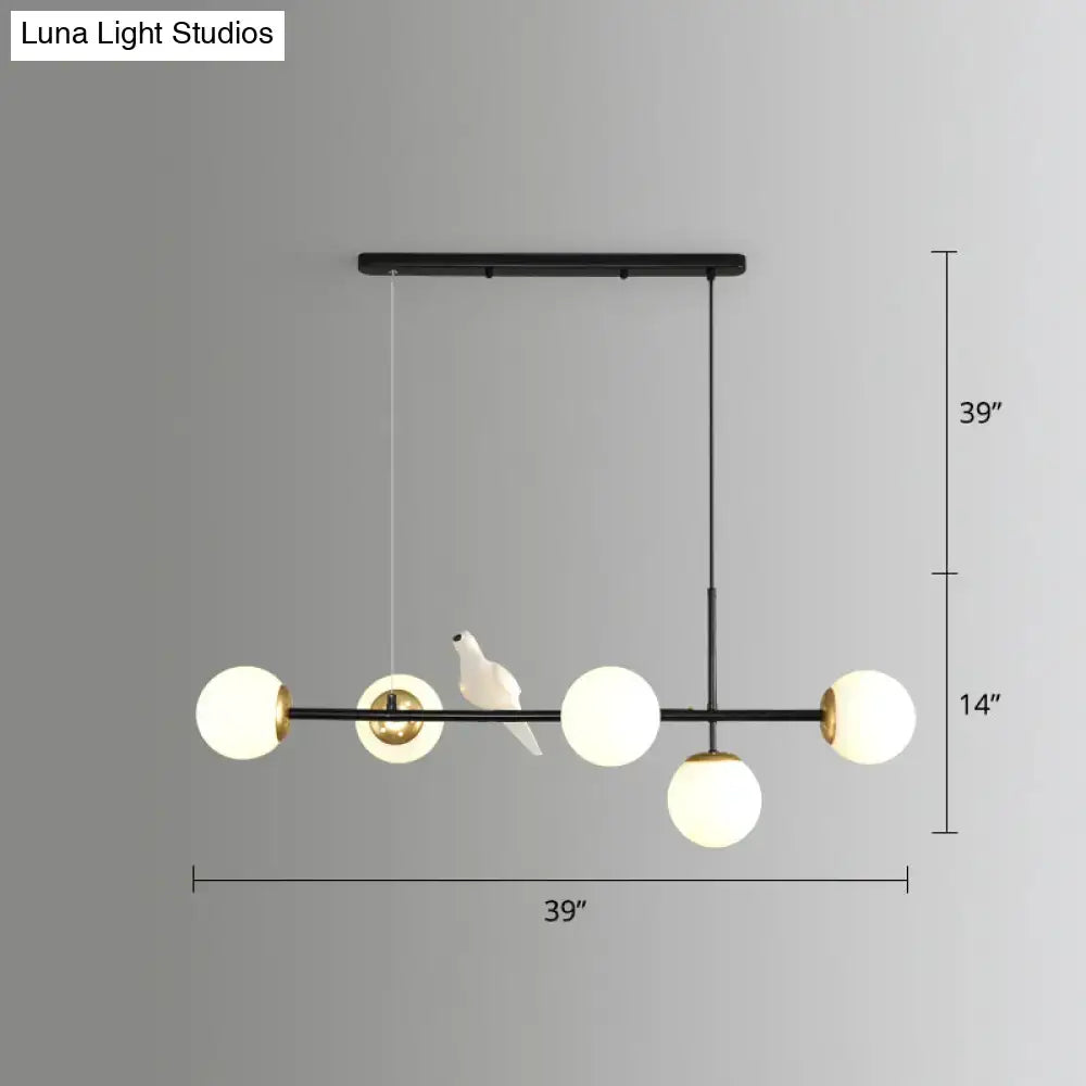 Black metal modo island chandelier with five milk white frosted glass globes and a white ceramic bird figurine