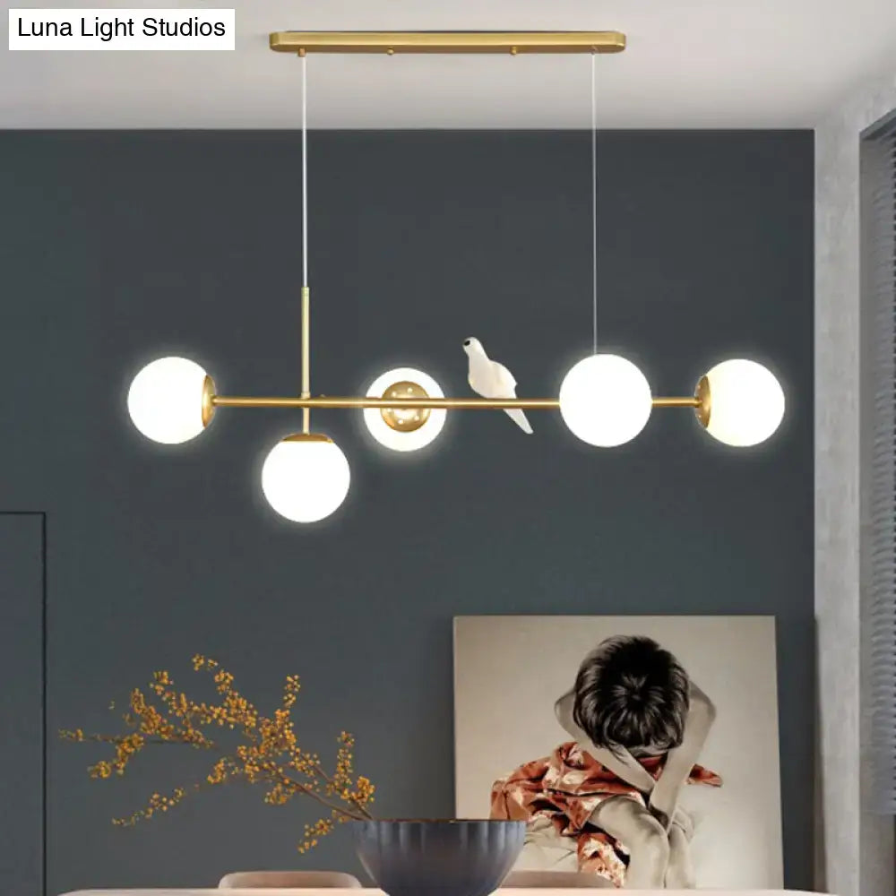 Modern gold-toned modo island 5-light pendant with spherical glass bulbs and a milk white ceramic dove for restaurants