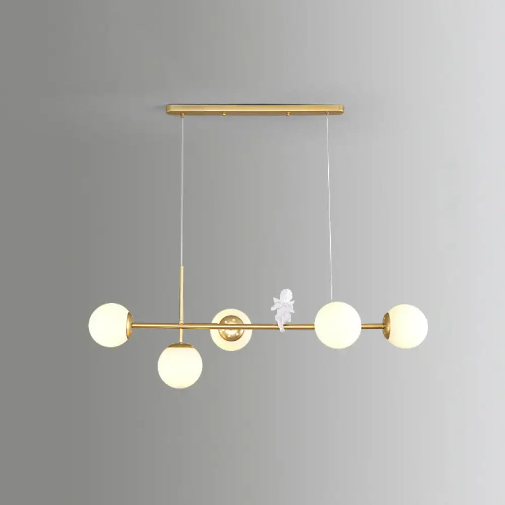 Decorbites modo island gold-toned pendant light with five milk white frosted glass globes and central angel figurine