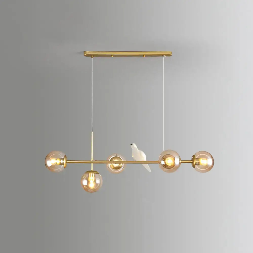 Modo island gold-toned 5-light pendant light with amber glass bulbs and milk white ceramic bird for restaurants