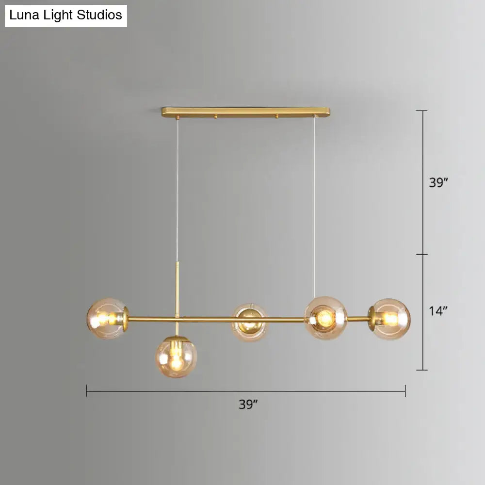 Gold-toned modo island 5-light pendant light with milk white glass bulbs suspended from a horizontal bar for restaurants